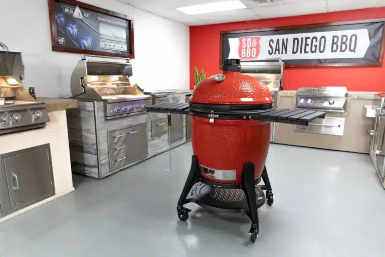 Modern red kamado grill in a showroom with BBQ accessories