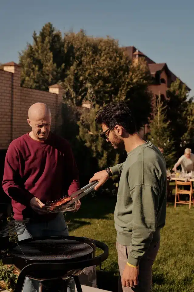 Friends enjoying backyard barbecue party on sunny day