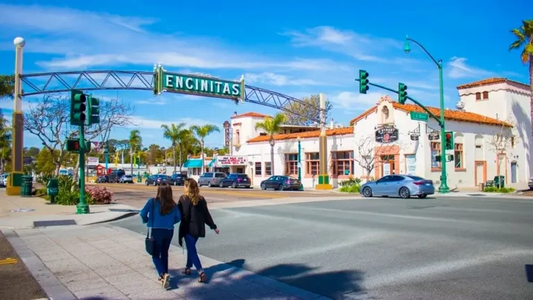 Encinitas Main Street with the iconic Encinitas sign, pedestrians, and historic buildings along the coastal town.