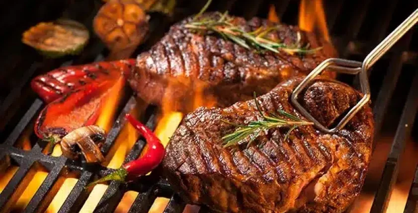 Flame-grilled steaks with vegetables on the grill