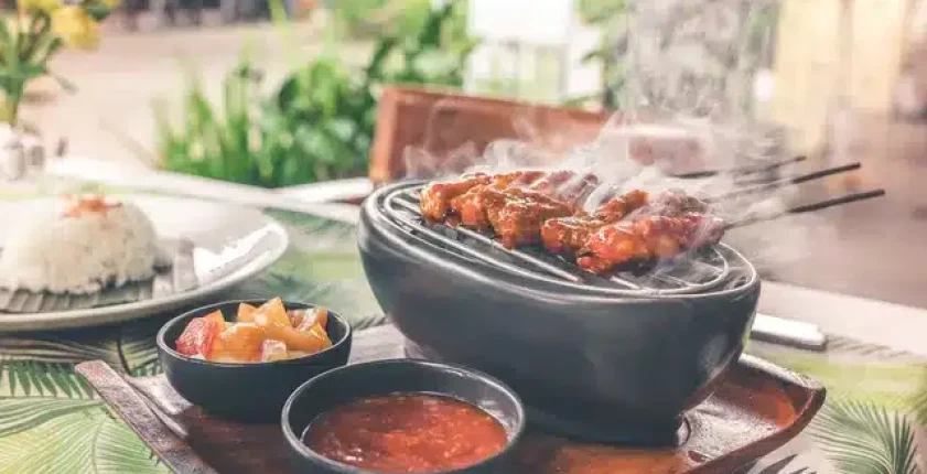 Sizzling grilled chicken wings in a clay pot