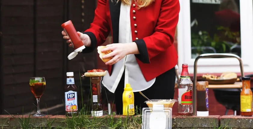 Woman dressing a hamburger at an outdoor picnic