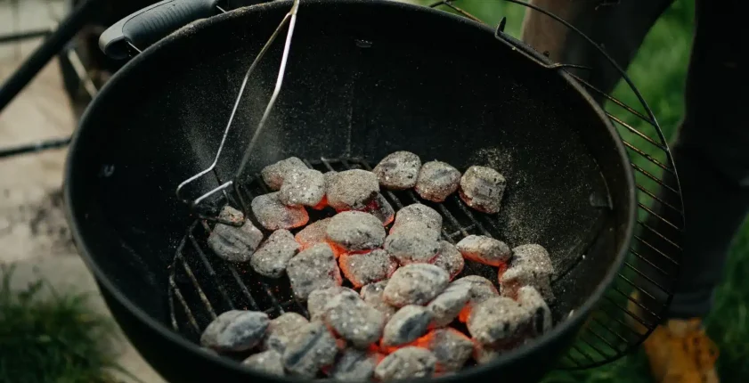 Charcoal briquettes glowing in a round grill